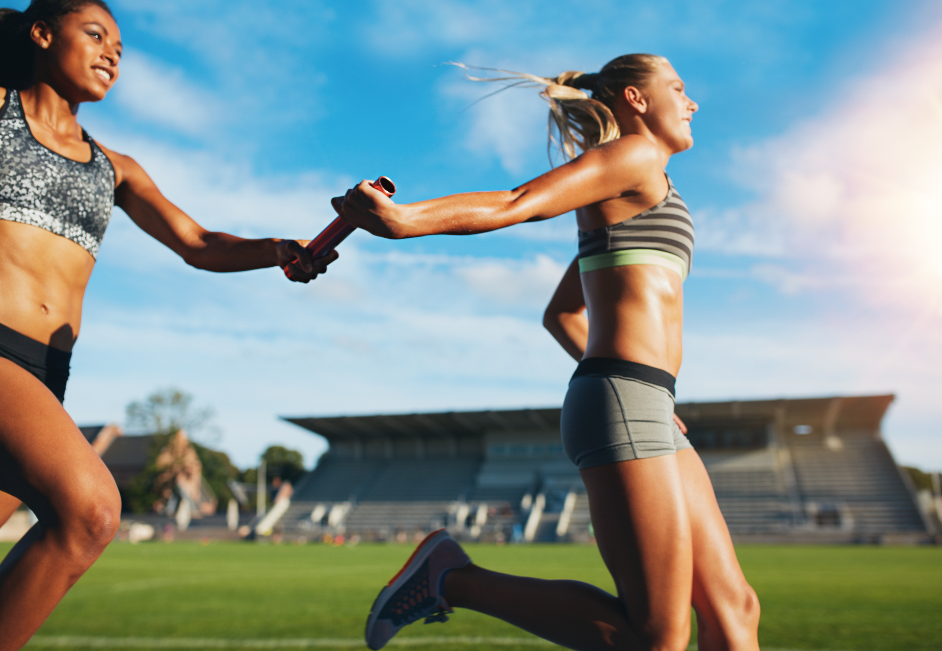 Relay runners passing a baton on a track field