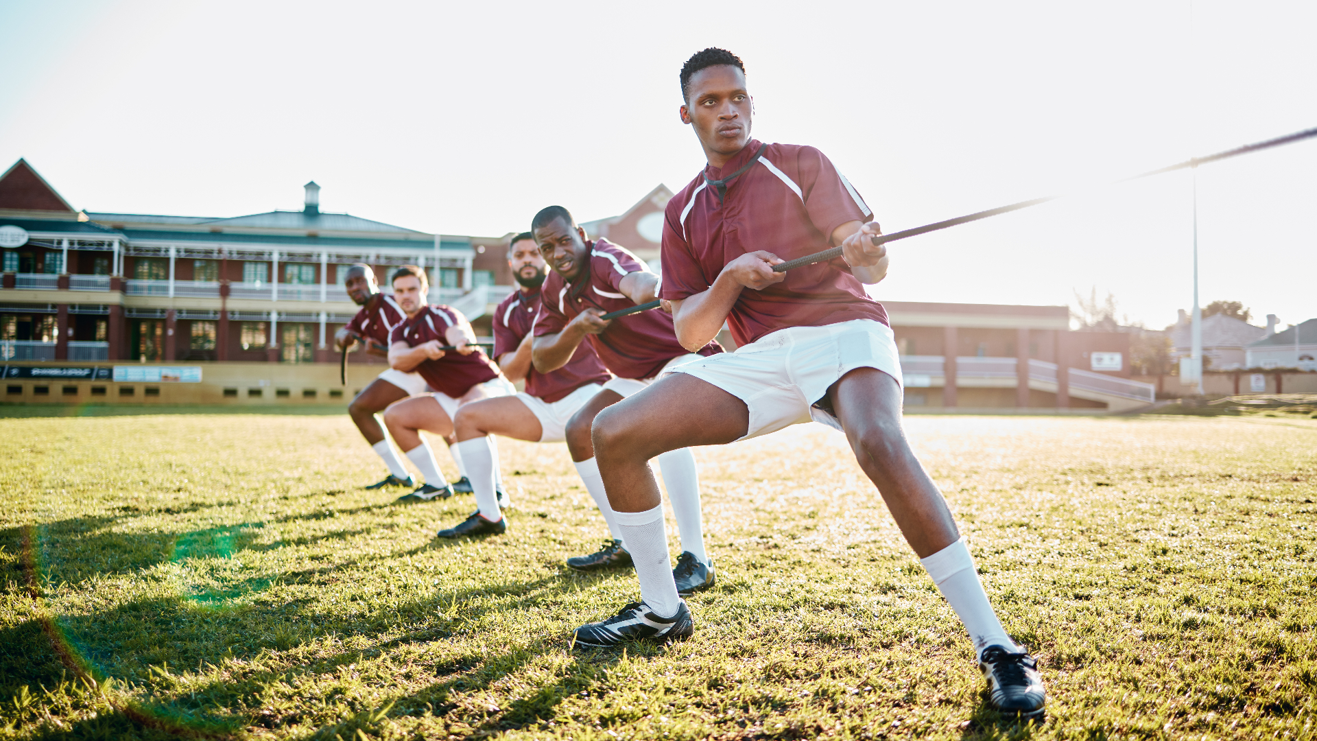 Athletes pulling together in a tug-of-war on a field